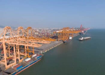 An aerial view of a large container ship docked at a port, promoting economic growth.