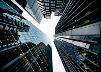 Low-angle view of modern skyscrapers reflecting light. Sustainable urban architecture. - Supply Chain News