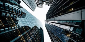 Low-angle view of modern skyscrapers reflecting light. Sustainable urban architecture. - Supply Chain News