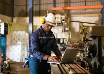 A man employing a strategic approach while working on a laptop in a manufacturing factory.