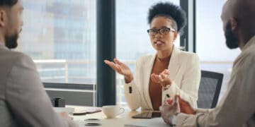 Three professionals in a meeting; a woman leads the discussion. - Supply Chain News