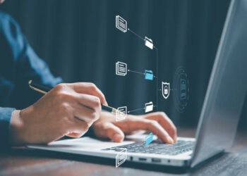 Person working on laptop, reviewing secure files. Enhanced KYC/AML protocols. - Supply Chain News