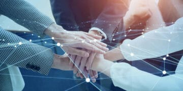 A group of business people putting their hands together in front of a network during the United States visit by Prime Minister Narendra Modi.