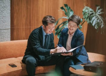 Two businesspeople review documents, demonstrating KYC procedures. - Supply Chain News