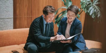 Two businesspeople review documents, demonstrating KYC procedures. - Supply Chain News