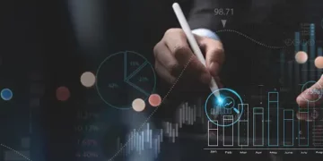 A man in a suit is holding a pen in front of an efficiency graph.