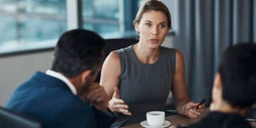 Three business professionals in discussion; a woman leads the conversation, preparing for 2024. - Supply Chain News