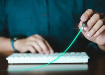 Person drawing upward trend graph on keyboard, symbolizing economic growth. - Supply Chain News