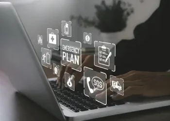 A person typing on a laptop with emergency plan icons, navigating the challenges of ransomware in various industries.