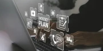 A person typing on a laptop with emergency plan icons, navigating the challenges of ransomware in various industries.