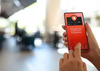 Smartphone displays unauthorized credit card transaction alert. WhatsApp scam warning. - Supply Chain News