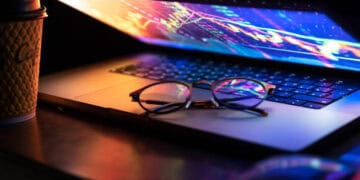 Laptop displaying stock market data; glasses rest on keyboard. Global trade analysis. - Supply Chain News