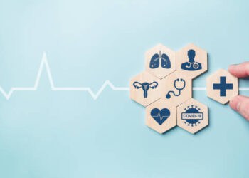 A hand holding a wooden block with medical icons on it amidst the pandemic.