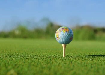 Golf ball with world map design on tee on green - Supply Chain News