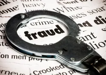 Handcuffs on newspaper with "fraud" highlighted; responding to financial crime. - Supply Chain News
