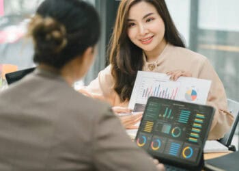 Two businesswomen reviewing financial charts, discussing Russia sanctions strategy. - Supply Chain News