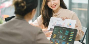 Two businesswomen reviewing financial charts, discussing Russia sanctions strategy. - Supply Chain News