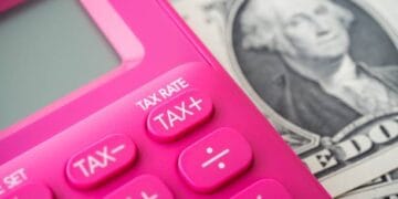 Pink calculator with tax buttons rests on US dollar bill; Tax Rate, Tax+, Tax- are visible. - Supply Chain News