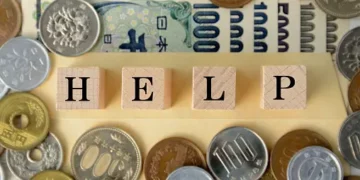 Wooden blocks spelling HELP surrounded by Japanese yen coins and banknotes. - Supply Chain News