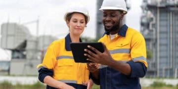Two engineers reviewing a tablet, improving risk management in factoring and receivables finance. - Supply Chain News