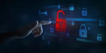 Hand reaching for unlocked red padlock among many locked blue padlocks; cybersecurity breach concept. - Supply Chain News