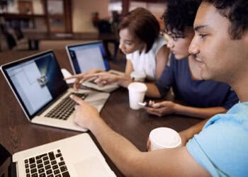 Three young adults collaborate on laptops, discussing Venezuela sanctions and their implications. - Supply Chain News