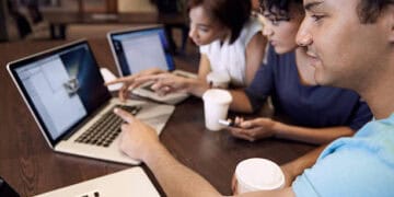 Three young adults collaborate on laptops, discussing Venezuela sanctions and their implications. - Supply Chain News