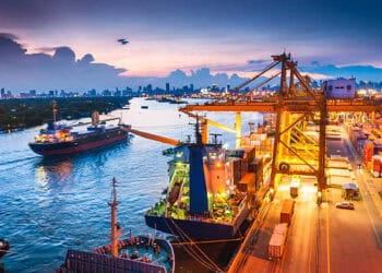 Busy cargo port at night, ships loading and unloading containers. Impact of Russian sanctions on European critical raw material imports. - Supply Chain News