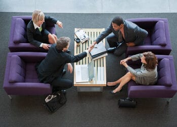 Four businesspeople shake hands at a tourism workshop, focused on customer understanding. - Supply Chain News