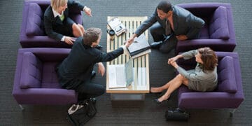 Four businesspeople shake hands at a tourism workshop, focused on customer understanding. - Supply Chain News