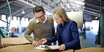 Two colleagues review HM Government's Strategic Export Controls Annual Report 2022. - Supply Chain News