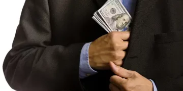 Man concealing cash in jacket pocket, illustrating potential PDAF misuse. - Supply Chain News