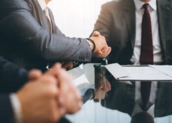 Businessmen shaking hands across a table with documents, signifying a potential Biden-Xi Jinping meeting. - Supply Chain News