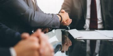 Businessmen shaking hands across a table with documents, signifying a potential Biden-Xi Jinping meeting. - Supply Chain News