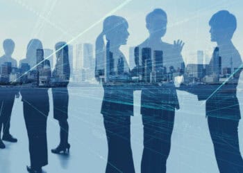 Evolving silhouettes of business people in front of a global city.