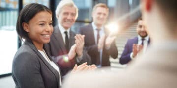 Businesspeople applauding a female colleague, celebrating success in AI risk management. - Supply Chain News