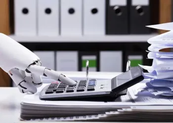 Robotic hand using calculator amidst paperwork; AI in accounting. - Supply Chain News