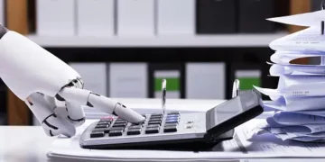 Robotic hand using calculator amidst paperwork; AI in accounting. - Supply Chain News