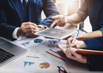 Businesspeople reviewing financial data on tablet, discussing new sanctions against Myanmar arms dealers and financiers. - Supply Chain News