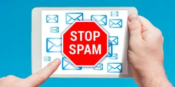 Hands holding tablet showing "STOP SPAM" sign surrounded by email icons. Combating spam calls and fraud. - Supply Chain News