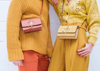 Two women wearing luxury fashion outfits, including yellow sweaters and orange pants.