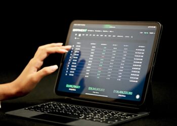 Person using tablet displaying Bittrex cryptocurrency exchange data, showing 7-day and 30-day volume. - Supply Chain News