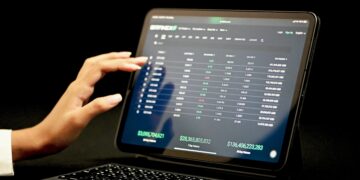 Person using tablet displaying Bittrex cryptocurrency exchange data, showing 7-day and 30-day volume. - Supply Chain News