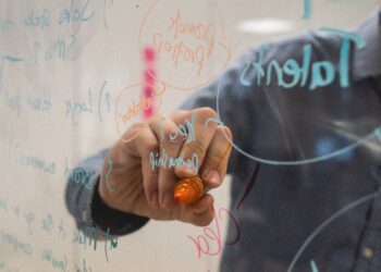 Person brainstorming blockchain data security solutions on a glass whiteboard. Keywords like "transparency" and "B2B ecosystem" are subtly incorporated into the written notes. - Supply Chain News