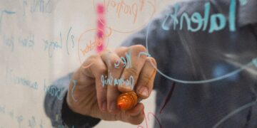 Person brainstorming blockchain data security solutions on a glass whiteboard. Keywords like "transparency" and "B2B ecosystem" are subtly incorporated into the written notes. - Supply Chain News