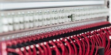 Close-up of fiber optic cables connected to a server rack. Login.gov data infrastructure. - Supply Chain News