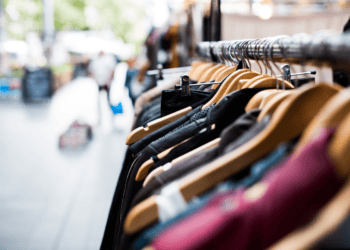 Luxury clothing on hangers in a boutique. Global luxury goods market trends 2023. - Supply Chain News