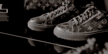 Luxury Louis Vuitton sneakers and bag on a dark surface. Challenges in the US luxury market. - Supply Chain News