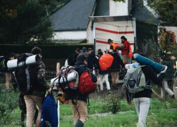 Hikers with backpacks walking away from a truck, possibly after a voluntary self-disclosure of sanctions violations. - Supply Chain News