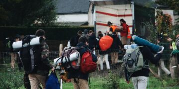 Hikers with backpacks walking away from a truck, possibly after a voluntary self-disclosure of sanctions violations. - Supply Chain News